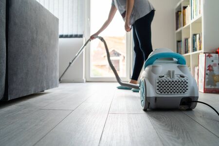 Young woman using vacuum cleaner at home cleaning