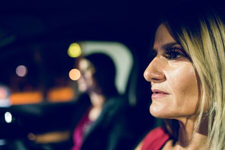 two women females in the car driving at night friends mother and daughter sisters