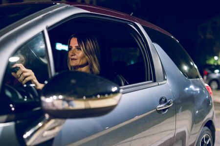 Woman female driver holding the wheel of the car driving in the night side view