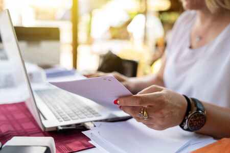 Freelancer woman working on her laptop entering data from document typing while sitting by the table...