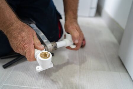 Close up on hands of plumber welding plastic pipes plumbing installation