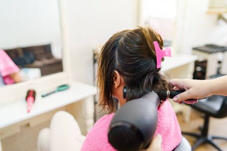 Professional female hairdresser drying woman's hair styling using blow dryer at the hairdressing saloonの写真素材