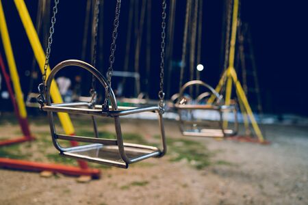 Empty chair on the chains of the swing ride attraction at the fun fair carousel amusement park in the nightの写真素材