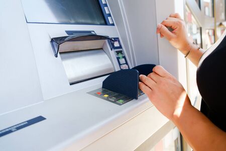 Close up on hands of caucasian woman at the atm taking paying bills money at the cash machine bank...
