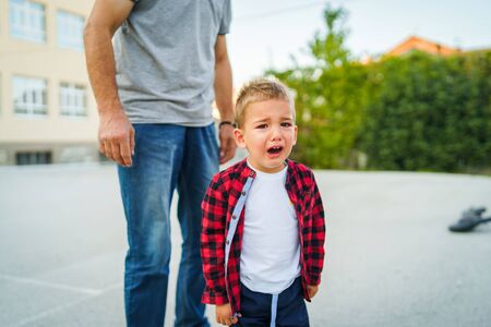 Little small boy crying with the senior man standing behind him threatening in the yard violence abuse in summer dayの写真素材