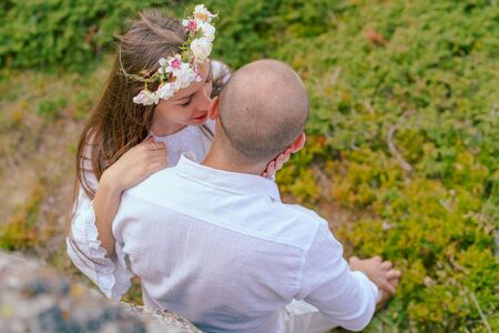 High angle view on young couple in love, she stands beside him and hug while kissing him or whisper...
