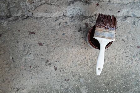 White brush with brown paint on the bucket on the ground on concrete background high angleの写真素材