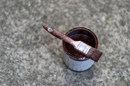 White brush with brown paint on the bucket on the ground on concrete background high angleの写真素材