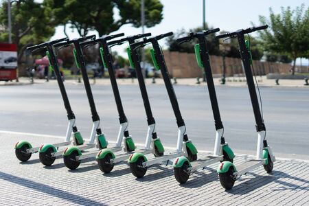 Lime Electric push kick scooter sharing rentals in sunny day by in a row scooters by the street on the sidewalk in a city thessaloniki ready to ride or rentの写真素材