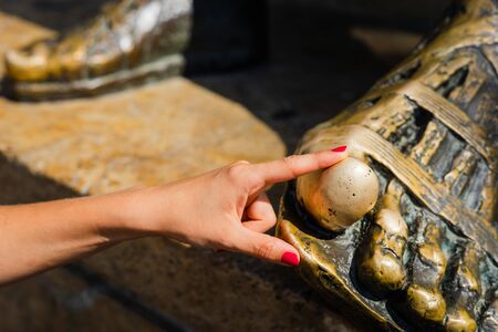 The foot of Aristotle monument in thessaloniki the thumb that you rub to get wisdom close up young woman touch the thumb tourist in sunny dayの写真素材
