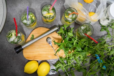 Drinking glasses on the table at the kitchen by the pile of lemon and mint herb ready for the mojito...