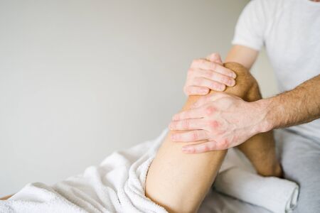 Young man male athlete having sport massage at spa or home by professional therapist relax body...