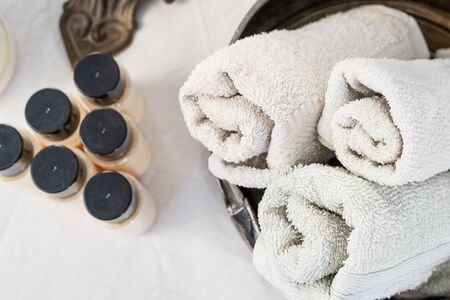 Close up on white rolled towels at spa saloon on the massage table by the essential oils bottles