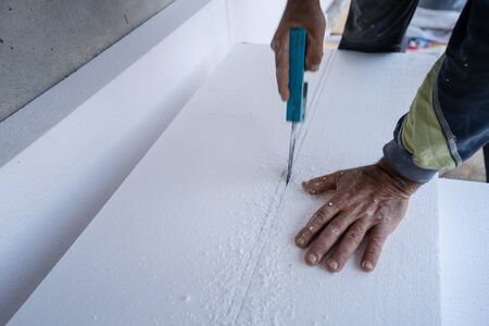 Construction worker using the hand saw to cut the  insulation panel table at the construction site in the insulating renovation procedureの写真素材