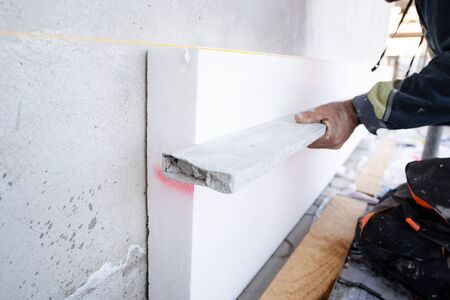 construction worker during the  house external wall insulation. Contractor with level checking the...