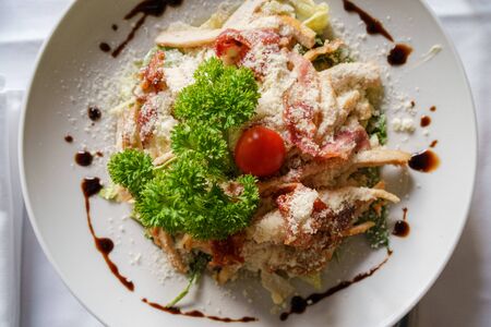 High angle top view on Caesar salad served in a white plate on the table fresh with some parsleyの写真素材