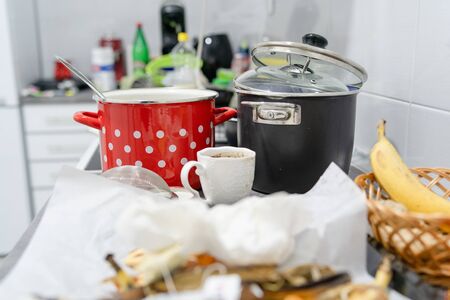 Side view on white kitchen with unwashed dirty pots and dishes on the countertop utensils and kitchen appliances in a mess after cookingの写真素材