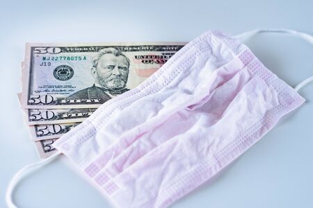 Top view on USD american dollar banknotes money on the table with protective medicine surgical mask...