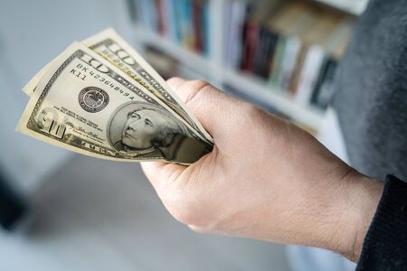 High angle close up view of unknown caucasian man midsection holding american dollars USD banknotes...