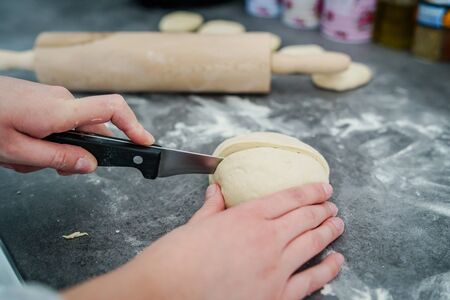 Close up on hand of unknown caucasian woman female girl making bread cutting the dough pastry using...