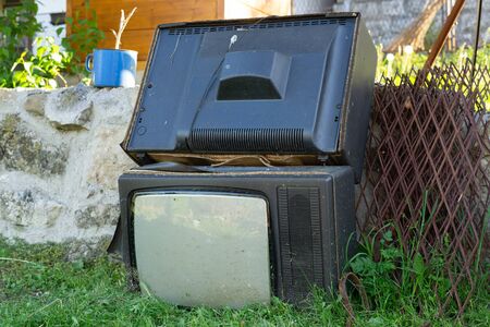 Discarded garbage Old TV set thrown by the wall and junk broken in day technology recycling electronic waste ready for recycle or to make a pollution two TVsの写真素材