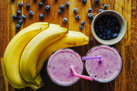 Top view on bananas and blueberries fruit smoothie on wooden tableの写真素材