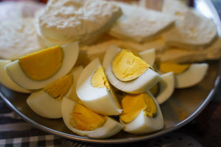 Close up on cut hard boiled eggs and cheese on plate served on the table ready to eat - fresh homemade organic food on farmの写真素材