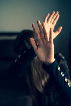 Close up on hands of unknown caucasian woman opened in front of her head to protect from strike -...