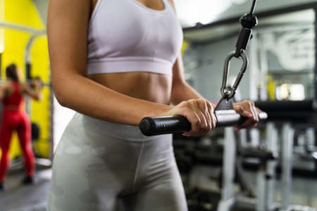 Close up midsection of unknown caucasian woman training arms at gym on machineの写真素材