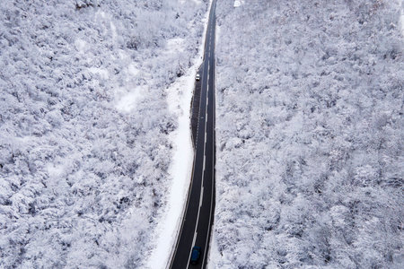 High angle aerial view drone image on the road trough the trees and forest in mountain range covered with white snow in winter day near Knjazevac in Serbia - Travel journey and vacation conceptの写真素材