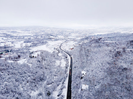 High angle aerial view drone image on the road trough the trees and forest in mountain range covered with white snow in winter day near Knjazevac in Serbia - Travel journey and vacation conceptの写真素材