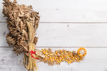 Top view on oak branches with wheat and corn seed and nuts on wooden table with copy space - orthodox christmas badnjak conceptの写真素材