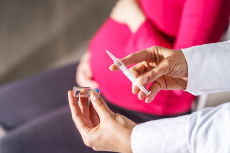 Vaccination healthcare concept - Hands of doctor or nurse hold a syringe and ampule preparing a shot of virus  hpv or flu vaccine for unknown pregnant patient - copy space close upの写真素材