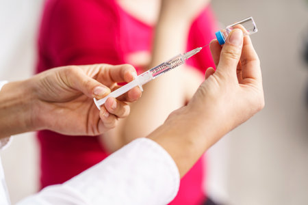 Vaccination healthcare concept - Hands of doctor or nurse hold a syringe and ampule preparing a shot of  hpv or flu vaccine for unknown patient - copy space close upの写真素材