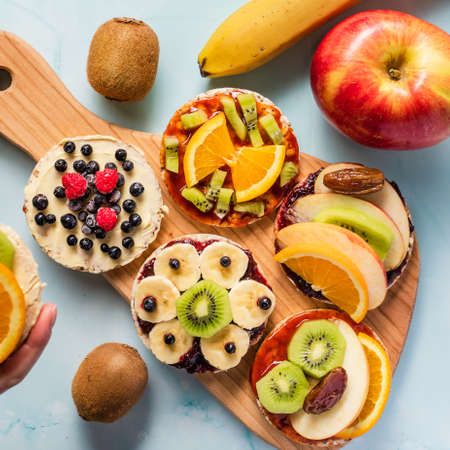 Crispy puffed rice cakes on table with fresh fruit kiwi banana apple blueberries raspberries and orange on the table - top view on healthy organic vegetarian or vegan breakfast gluten freeの写真素材