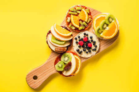 Crispy puffed rice cakes on board with fresh fruit kiwi banana apple blueberries raspberries and...