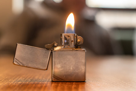 Front view on metal lighter on the table lighting fire in dayの写真素材