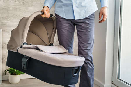Caucasian man holding baby sleeping basket at home in day - parenthood conceptの写真素材