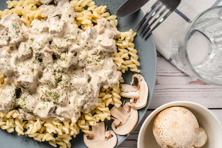 Tagliatelle Italian pasta with forest white champignon mushrooms creamy sauce and chicken or beef meat - homemade food in plate on the table top view close upの写真素材