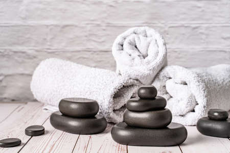 Spa stones for massage by white towels on wooden table copy space