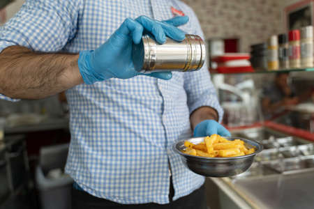 Close up on hands midsection of unknown man entrepreneur with blue rubber protective glove salting...