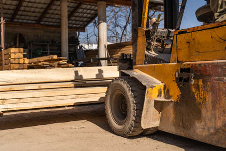 Fork lifter at warehouse lifting timber planks in sunny day no peopleの写真素材