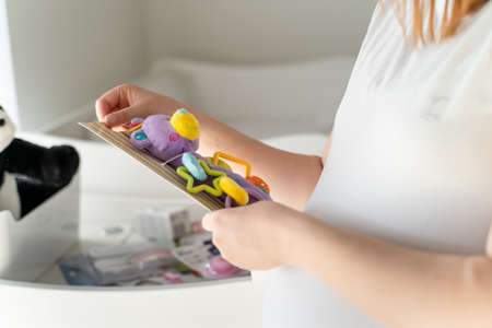 Close up on hands of unknown caucasian pregnant woman holding a toy in bright room - maternity and pregnancy expectations conceptの写真素材