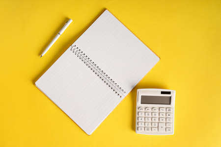Office book with a pencil and a calculator on a yellow backgroundの写真素材