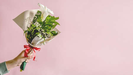Hands of unknown caucasian woman holding bouquet of decorated Calla Zantedeschia flower in front of...