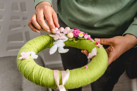 Close up on homemade yarn Crocheted Easter wreath DIY wool decoration hobby craft in hands of unknown caucasian woman making present decoration - hobby and holiday celebration conceptの写真素材