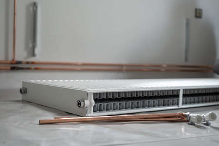 Central heating pipes and radiator on the floor at construction site in apartment house or building...
