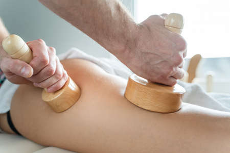Close up on back of unknown woman having madero therapy massage anti-cellulite treatment by...