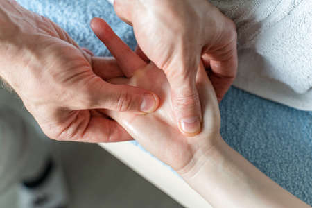 Close up on hands of unknown caucasian man therapist massaging and stretching hands of unknown woman...