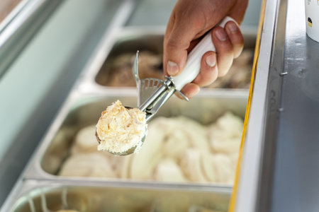 Close up on hand of unknown man holding a ball of ice cream in the refrigerator on the street saleの写真素材